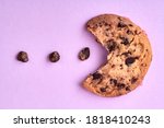 Small photo of Chocolate cookie packman. Cookie diagram and chocolate grains isolated on purple background.