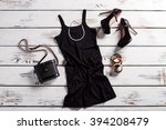 Black dress, shoes and jewelry. Black female outfit on table. Glamorous dark clothes with purse. Retro purse and modern clothing.