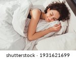 Small photo of Woman sleeping. High angle view of beautiful young woman lying in bed and keeping eyes closed while covered with blanket. Stock photo