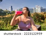 Portrait view of the curvy brunette woman drinking water after running