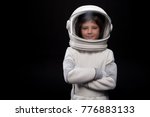 Cosmonaut concept. Waist up portrait of positive little boy wearing white armor and helmet is standing with crossed arms while looking at camera with joy. Isolated background with copy space