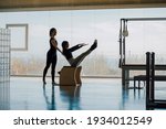 Small photo of Happy Smiling Fitness instructor and student working out in a big gymnasium, Pilates health club, with wide windows and outside views. Personal trainer correcting posture, helping client with exercise