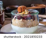 Granola with roasted oatmeal and puffed amaranth served with fruits and greek yogurt and topped with almonds and honey in a glass bowl