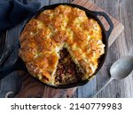 Small photo of Savory pie with minced meat and cabbage. Topped with baked mash potato crust and cheddar cheese. Served in cast iron skillet on wooden table. Table top view