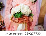 close up of  bride's hand with henna painted wearing wedding ring holding a rose bouquet in traditional Islamic wedding
