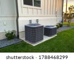 Double AC units outside white brick home with green landscape and gravel