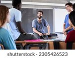 Small photo of Secondary student being helped by professor in classroom. Malee caucasian teacher helping guys during after class. High school girls and boys talking for explanations to helpful. . High quality photo