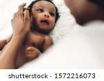 African american mother playing with adorable little african american baby in a white bedroom.Love of black family concept