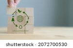 Small photo of Circular economy concept, recycle, environment, reuse, manufacturing, waste, consumer, resource. 3rd.Sustainable development. Hand put wooden cubes; the symbols of circular economy on grey background.
