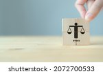Small photo of Business ethics concept. Business moral principles concept. Hand holds the wooden cubes with "ETHICS" symbols on grey background and copy space. Banner for business integrity, good governance policy.