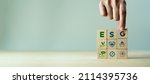 Small photo of ESG concept of environmental, social and governance. Sustainable corporation development. Hand holds wooden cubes with abbreviation ESG standing with other ESG icons on grey background. Copy space.
