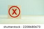 Small photo of Red cross mark, x, wrong mark sign, Rejection sign in wooden cube stack. Concept of negative decision making or choice of vote, againt, resist, contravene the law, regulatory, non-compliance concept.