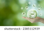 Small photo of Environmental tax breaks concept. Holding glass ball with green tax icons. Using environmental taxes, carbon tax, environmentally beneficial tax incentives in order to achieve environmental targets.