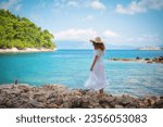 The girl with the hat in the white dress on the beach enjoys the beautiful view of the Adriatic Sea, on the island of Mljet in the national park