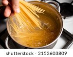 Small photo of Dip spaghetti into boiling water in a saucepan. Pasta cooking.