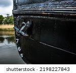 Small photo of The bow of a ship showing anchor and plimsoll depth gauge numbers.