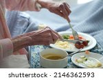 Small photo of Elderly lady eating healthy lunch in bed. Old age home. Frail care. vegetables. Sausage. Soup.