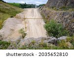 Small photo of A view over Ballidon Quarry in the White Peak area of Derbyshire. A deserted earth road with rather incongruous road signs leads between high hills towards a processing works.