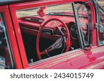 Close up of an australian red retro chevrolet car steering wheel and control panel. View from the window.