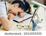 Small photo of An exhausted professional woman doctor has succumbed to sleep at her work desk, pen still in hand, amidst paperwork, signaling long hours and fatigue.