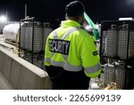 Small photo of A security guard is patrolling a commercial storage area at night.