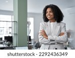 Small photo of Happy smiling portrait of young African American leader manager, stands confident, crossed arms and looking aside in business office center. Portrait of professional business woman in stylish suit.