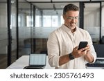 Small photo of Copy space are with smiling mature Latin or Indian businessman holding smartphone in office. Middle aged manager using cell phone mobile app. Digital technology application and solutions for business.