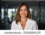 Small photo of Headshot close up portrait of latin hispanic confident mature good looking middle age leader, ceo female businesswoman on blur office background. Gorgeous beautiful business woman smiling at camera.