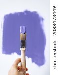 Small photo of Process of choosing paint for the walls during house renovation, violet very peri color and brush in paint, color of the year 2022
