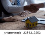 Small photo of Close up focus on small house model standing on table with clients signing contract agreement with real estate agent, purchasing own dwelling apartment, professional service concept.