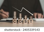 Small photo of Cost reduction concept. Cost wording on decreasing coins stacking with the down arrow. Businessman working on company cost saving. Cost Management, Economy recession, low budget, Effective business