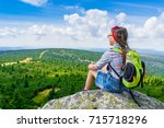 Young travel girl sitting on the rock mountain with backpack, relaxing - teen hiker girl relaxing and enjoying valley view 