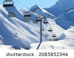 An empty chairlift on a background of snowy slopes and blue sky. Winter landscape of the ski resort. Winter sports during the vacations