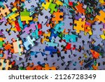 Small photo of Top view many jigsaw puzzle pieces over the entire frame. A background image of scattered colorful puzzle pieces