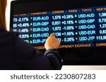 Computer monitor with currency exchange rates. Woman points her finger at the monitor. Currencies like usd, EUR, GBP, JPY and CHF on the screen. Banking, busines, trading, exchange and investment.