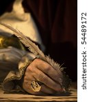 Small photo of A senior man's hand holding a quill and wearing a signet ring with seal