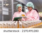 Indian engineers drink factory glass bottles Inspecting production fruit juice drinks that have been produced in large numbers by wearing tight protective clothing order best quality before being sell