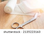 Small photo of Dressing or clean wound tools includes Roll gauze,pile of gauzes and gauze roll cutter or scissors with sun flare