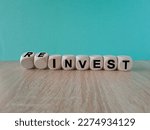Reinvest symbol. Inverted wooden cubes with words 'invest - reinvest'. Beautiful blue background. Business and reinvest concept. Copy space.
