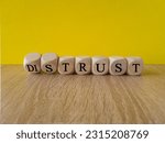 Small photo of Distrust or trust symbol. Turned wooden cubes, changes words 'distrust' to 'trust'. Beautiful wooden table, yellow background. Business and distrust or trust concept, copy space.