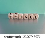 Small photo of Inhale, Exhale concept. Turned a dice and changes the word INHALE to EXHALE. Beautiful blue background, grey table, copy space. Business and INHALE or EXHALE concept.