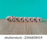 Small photo of Sympathy or empathy symbol. Turned wooden cubes and changed the concept word Empathy to Sympathy. Beautiful grey table blue background. Copy space. Psychological sympathy or empathy concept.