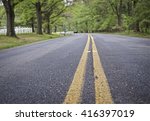 Small photo of DOUBLE YELLOW LINE ON ASPHALT ROAD, USA (THE IMAGE HAS SHALLOW DEPTH OF FIELD, FOCUS AT IMMEDIATE FOREGROUND)