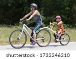 Small photo of Austin, Texas - 6 May 2020: a woman pulling a girl on a tag along bike attachment