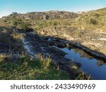 Small photo of Watercourse between beautiful rocks and mountains, with dark waters and lots of vegetation around, located in the rural region of Tres Barras, municipality of Serro, Minas Gerais, Brazil.