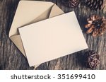 Blank white paper card with brown envelop and pine cones on old wooden table with vintage and vignette tone