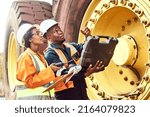 Small photo of Two African Mine workers are discussing maintenance on a large haul dump truck