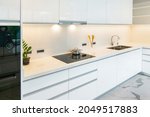 Small photo of Modern white kitchen with granite countertops and white cabinet. Have modern black induction hob, cooker, Built-in hood, Sink ,tap water in kitchen. White tone and clean kitchen