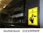 Small photo of selective focus Warning label affixed to printing platen covers in a printing house. Careful hands can get stuck. danger of breaking fingers when the machine is in print. Work safety