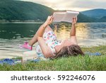 Young Woman Reading A Book By...